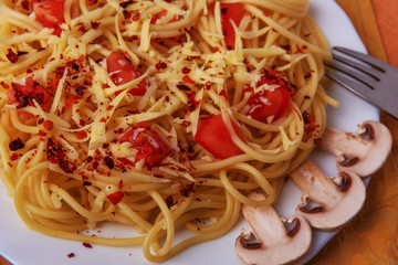 Dish for the restaurant menu, namely pasta with grated cheese and tomatoes with slices of mushrooms and spices in a design of green onions.