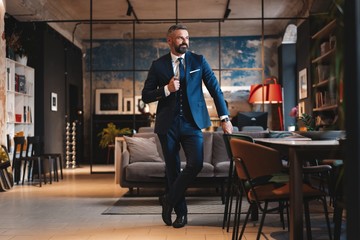Stylish bearded man in a suit standing in modern office