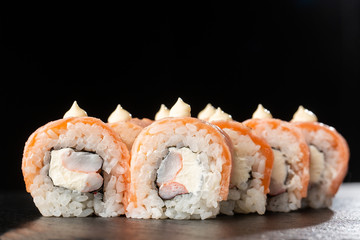 Sushi Rolls with flamed salmon, shrimp, crab meat and Cream Cheese inside on black slate isolated. Philadelphia roll sushi with shrimp. Sushi menu. Horizontal photo.