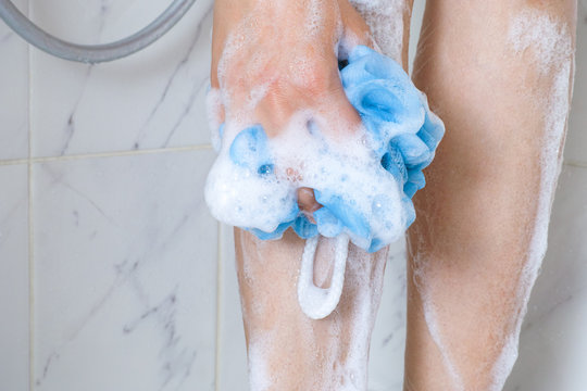 Woman With Sponge Washing Legs In Shower Bath.