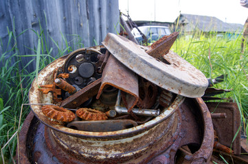 rusty scrap metal lies in tall grass