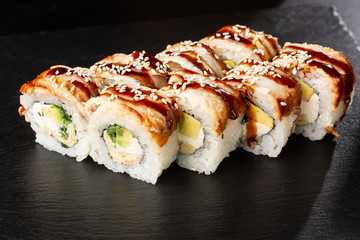Sushi Rolls with cucumber, avocado, eel, omelet and Cream Cheese inside on black slate isolated. Philadelphia unagi roll sushi with tamago. Sushi menu. Horizontal photo.