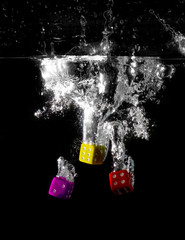 Three dice multicoloured splashing underwater 