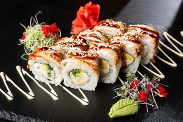 Sushi Rolls with cucumber, avocado, eel, omelet and Cream Cheese inside on black slate isolated. Philadelphia unagi roll sushi with tamago. Sushi menu. Horizontal photo.