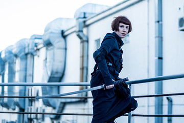 portrait of young redhead woman with japanese sword dressed in futuristic cyberpunk costume standing on the roof. 