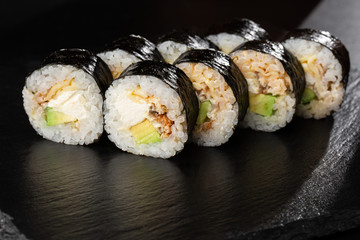 Sushi Rolls with eel, avocado, omelet and Cream Cheese inside. Maki Futomaki Sushi Rolls with eel on black background. Sushi menu. Japanese food. Horizontal photo.