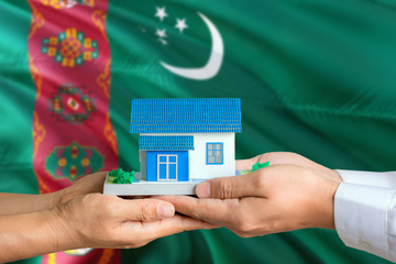 Turkmenistan real estate concept. Man and woman holding miniature house in hands. Citizenship theme...