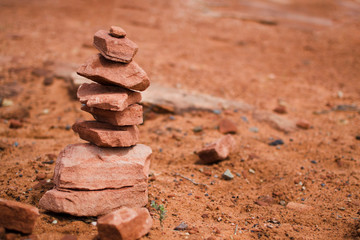 Fototapeta na wymiar Orange cairn closeup. Traveling in america, national park in arizona, desert. Trekking touristic. Sign of a visited place. A lot of terracotta pebbles, a stone tower.