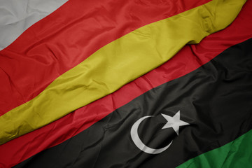 waving colorful flag of libya and national flag of south ossetia.