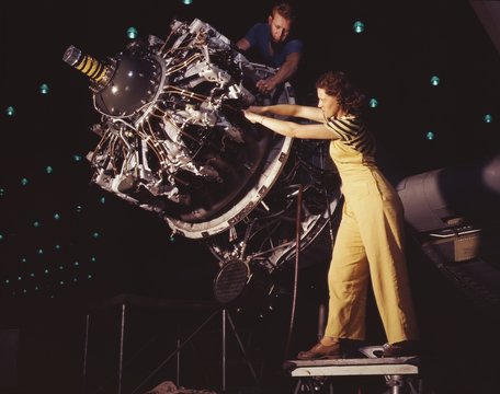 Woman war worker performing precise aircraft engine installation detail. Douglas Aircraft Company