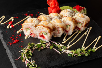 Sushi Rolls with cucumber, flying fish caviar, eel, omelet and Cream Cheese inside on black slate isolated. Philadelphia unagi roll sushi with tamago. Sushi menu. Horizontal photo.