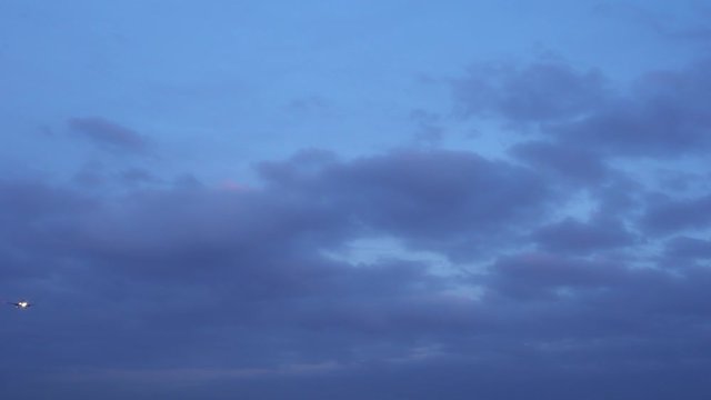 The plane flies in the evening sky. Dusk. Dark blue clouds. The airplane is landing, released the landing gear. Ultra HD stock footage