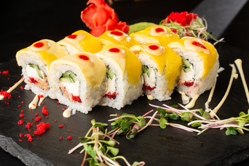 Sushi Rolls with cucumber, cheddar, flying fish caviar , tuna and Cream Cheese inside on black slate isolated. Philadelphia cheddar roll sushi with tuna. Sushi menu. Horizontal photo.