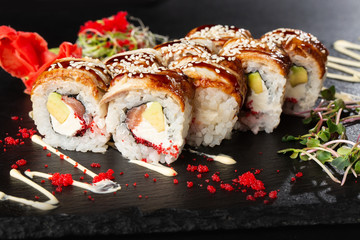Sushi Rolls with salmon, avocado, eel, flying fish caviar and Cream Cheese inside on black slate isolated. Philadelphia unagi roll sushi with salmon. Sushi menu. Horizontal photo.