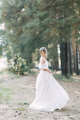 Fototapeta premium Elegant ceremony in European style. Beautiful bride in white flying dress in the forest.