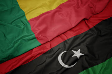 waving colorful flag of libya and national flag of benin.