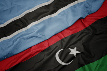 waving colorful flag of libya and national flag of botswana.