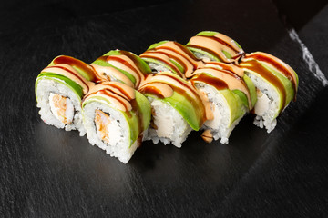 Sushi Rolls with grilled tempura shrimps, avocado, omelet and Cream Cheese inside. Philadelphia roll with tempura shrimps on black background. Sushi menu. Japanese food. Horizontal photo.