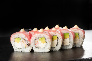 Sushi Rolls with avocado,tuna, shrimp, crab meat and Cream Cheese inside on black slate isolated. Philadelphia roll sushi with tuna. Sushi menu. Horizontal photo.