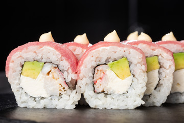 Sushi Rolls with avocado,tuna, shrimp, crab meat and Cream Cheese inside on black slate isolated. Philadelphia roll sushi with tuna. Sushi menu. Horizontal photo.