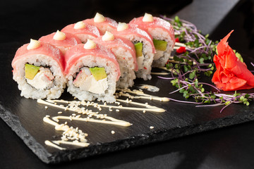 Sushi Rolls with avocado,tuna, shrimp, crab meat and Cream Cheese inside on black slate isolated. Philadelphia roll sushi with tuna. Sushi menu. Horizontal photo.