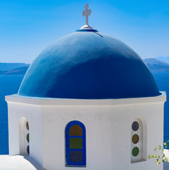 Fototapeta na wymiar Beautiful view of white typical village and Aegean Sea i. View of blue domed churches -famous tourist attraction in Greece.
