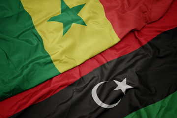waving colorful flag of libya and national flag of senegal.