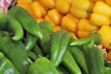 closeup of yellow and green peppers on display at the market