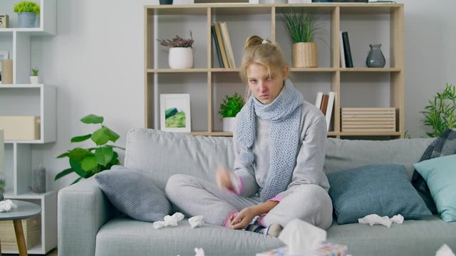 Girl wipes her nose with a napkin and looks at the camera