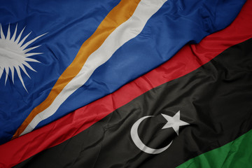 waving colorful flag of libya and national flag of Marshall Islands .