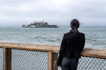 Young girl gazing at Alcatraz from San Francisco Pier - San Francisco, California, USA
