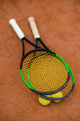 Tennis rackets and balls on the ground of an outdoor court.
