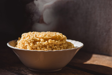 The smoke was poured from the boiled instant yellow noodles that had been boiled in hot water and brought out from a boiling pot in a bowl to be prepared as a food menu.
