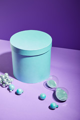 blue gift box and decorative baubles and hourglass on purple background