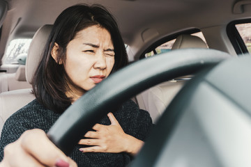 Asian woman suffering from heart attack while driving the car 