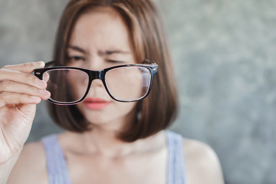 Asian woman holding eyeglasses having problem with eye blur vison