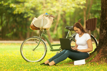  Woman spend the holidays cycling, reading books. Check email in notebook in the garden on a bright day.
