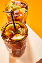 selective focus of cocktail cuba libre in glass with straw on cube