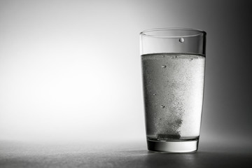 Closeup of effervescent tablets dissolving in a glass of water