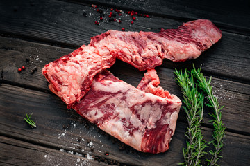 Raw machete beef steak with seasonings on old wooden background