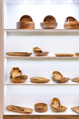 Wooden dishes. Kitchen utensils and accessories made of bamboo. Eco-friendly products. Various salad bowls, dishes, plates, food trays and spoons on a showcase shelf in a store