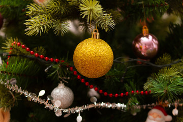 Golden ball on christmas tree. Christmas tree beads and garlands. New Year decor