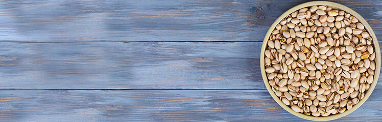Pistachio nuts on wooden background. Roasted salted pistachios. Top view.