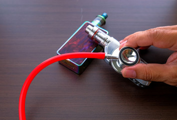 Conceptual image of uncertainty of health safety of e-cigarettes. Isolated close-up hand holding...