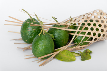 kaffir lime balls in  a round bamboo basket on a white scene