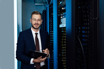 Fototapeta premium happy businessman in glasses holding clipboard in data center