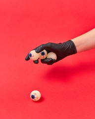 Woman hand in black glove with human eyeballs.