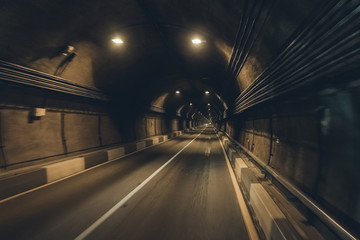 Road tunnel in mountain illuminated by lamps