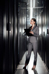 beautiful businesswoman holding clipboard while standing in data center