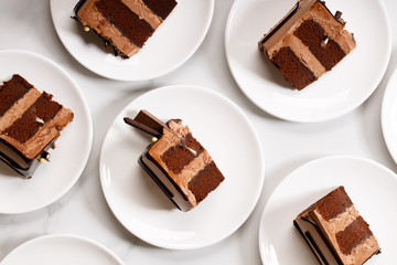 Pieces of layered dark chocolate cake on white plate